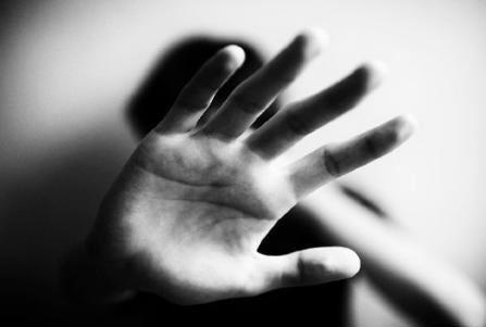 Black and white image. Close-up of a hand held up in front of a person